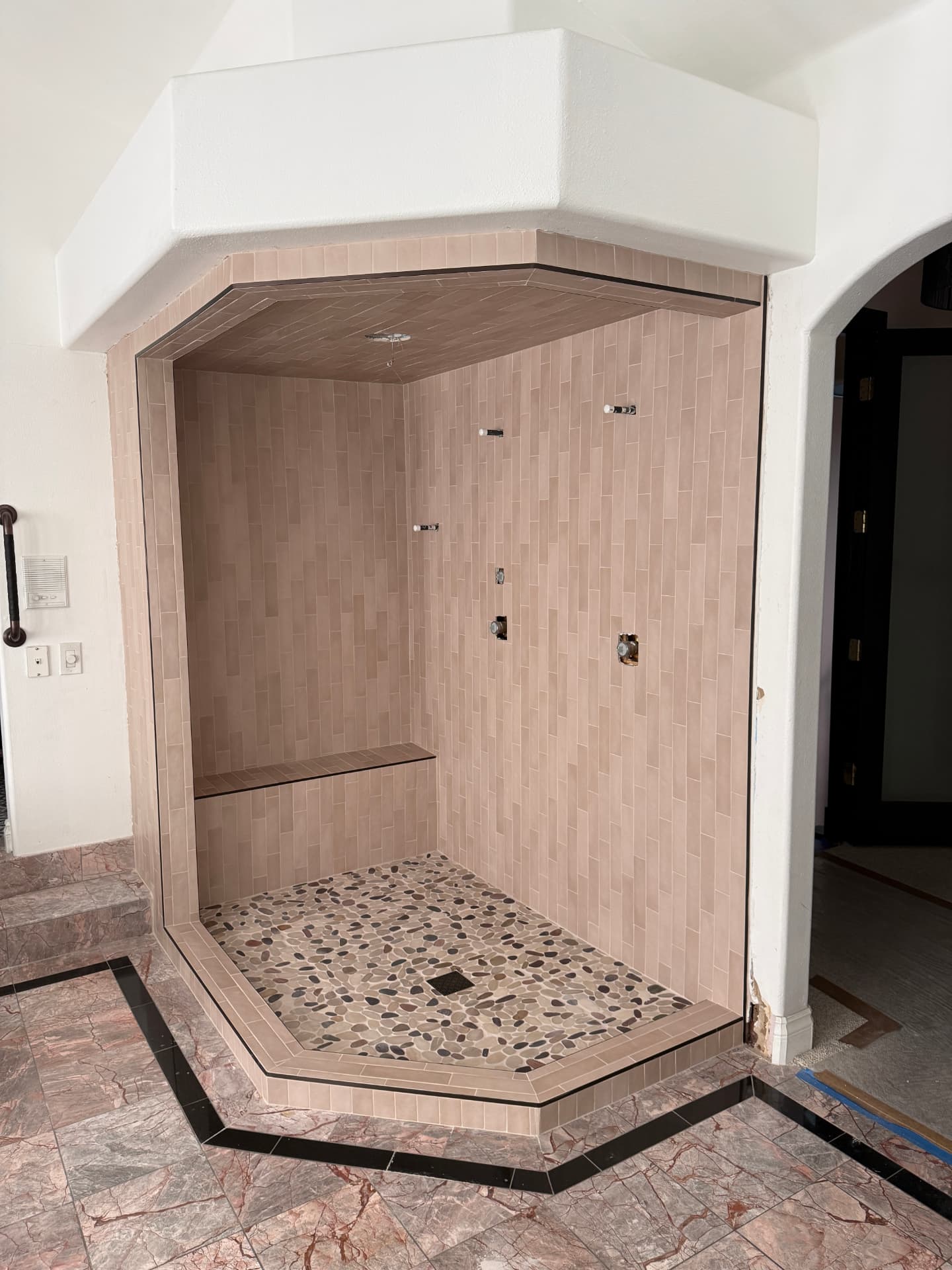 Corner shower with pebble mosaic pan and tiled bench