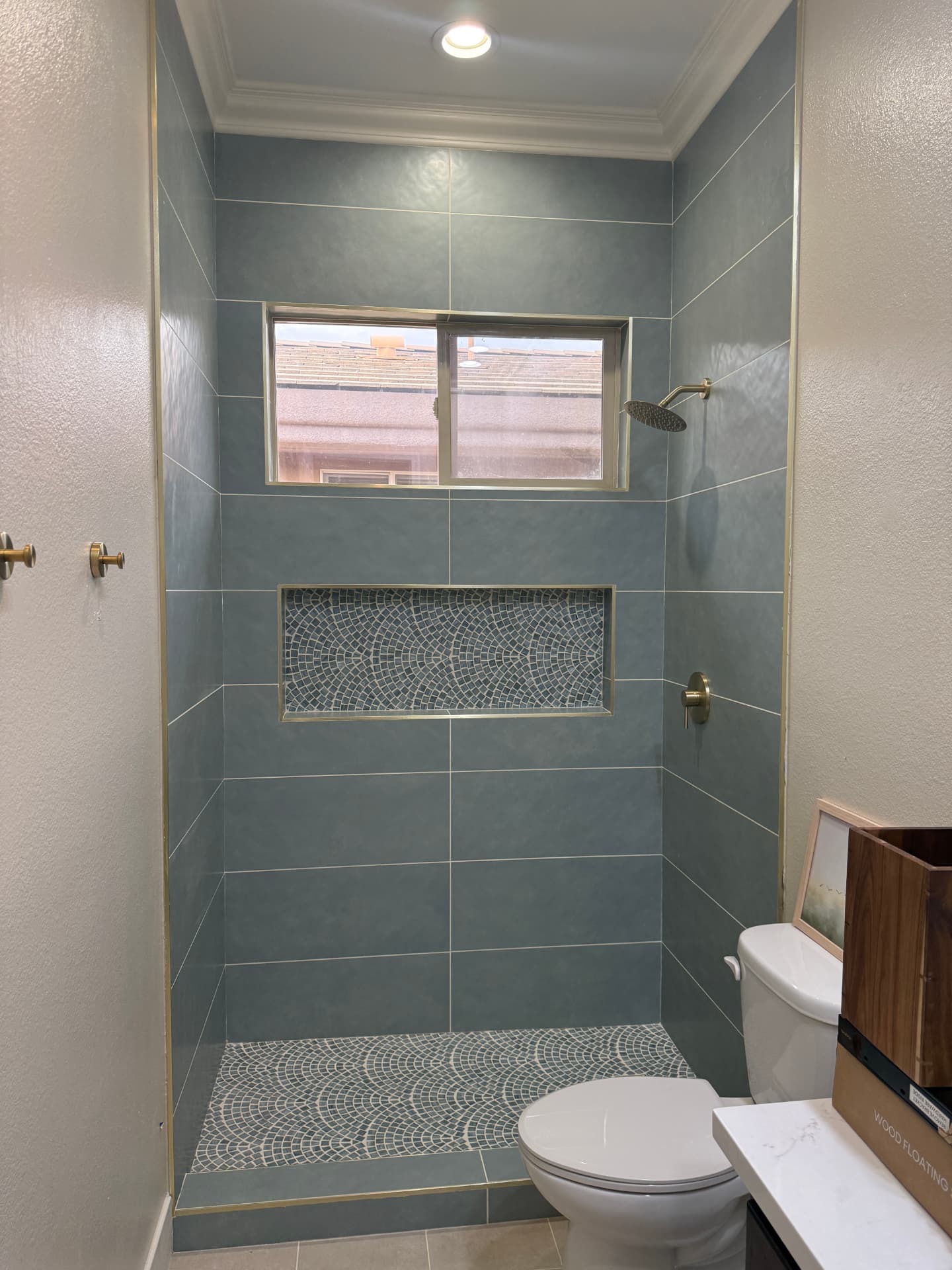 Blue tile shower with mosaic accent niche and gold trim